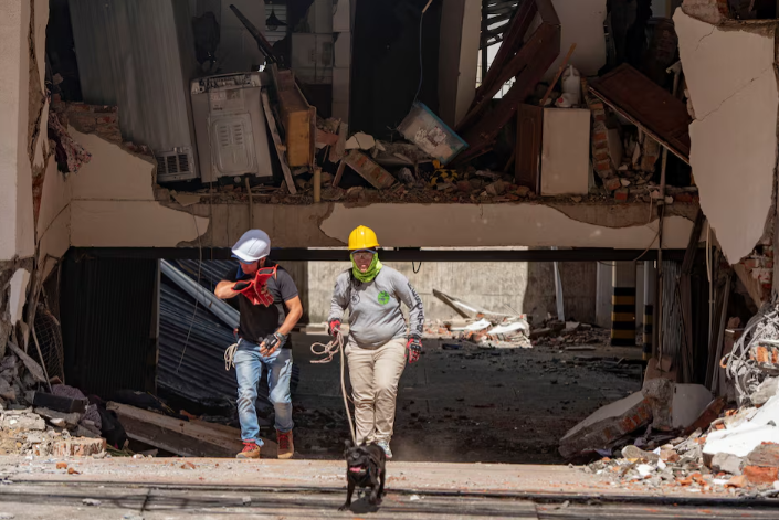 Rescue workers walk by a damaged building after an earthquake, in Cali,
