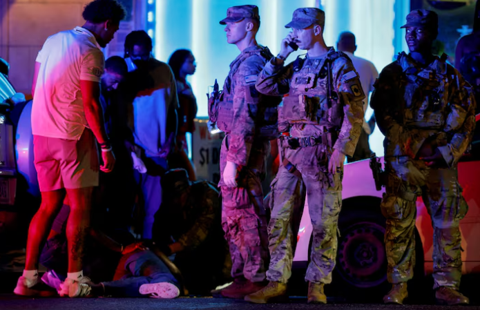 National Guard troops secure a scene as one of their own tends to an unresponsive person