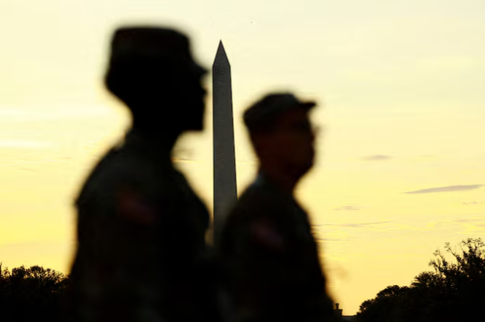 U.S. military members walk near the Washington Monument