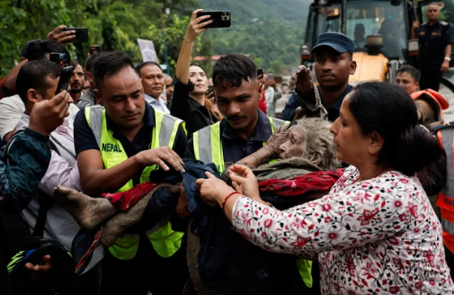 Police officers carry an elderly survivor to a safer place