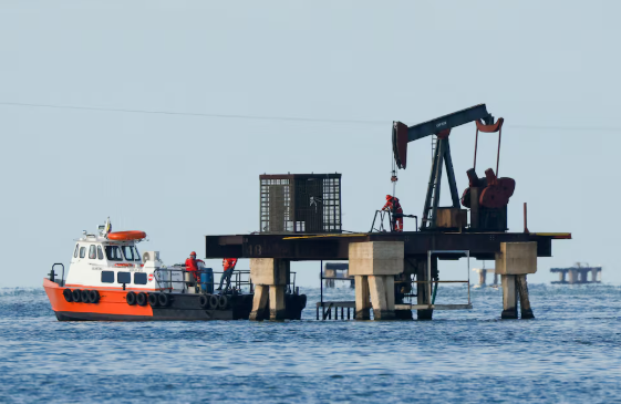 Workers of Venezuelan state oil company PDVSA labour at an operating pumpjack in Lake Maracaibo, in Cabimas, Venezuela