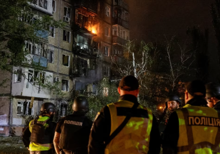 Police officers stand at a site of an apartment building hit by a Russian drone strike