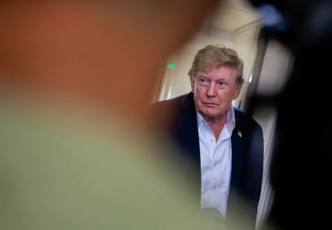 US President Donald Trump listens to members of the media aboard Air Force One
