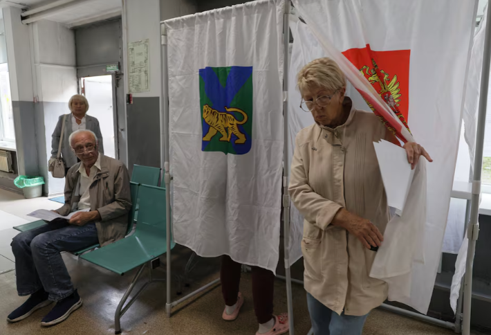 A voter leaves a voting booth before casting her ballot at a polling station on the final day of Russia's parliamentary election in Vladivostok